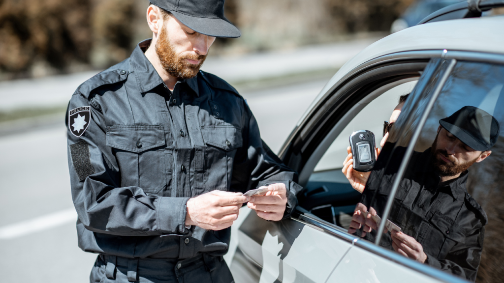 車の中でアルコールチェックする人と警察官のような人がいる画像